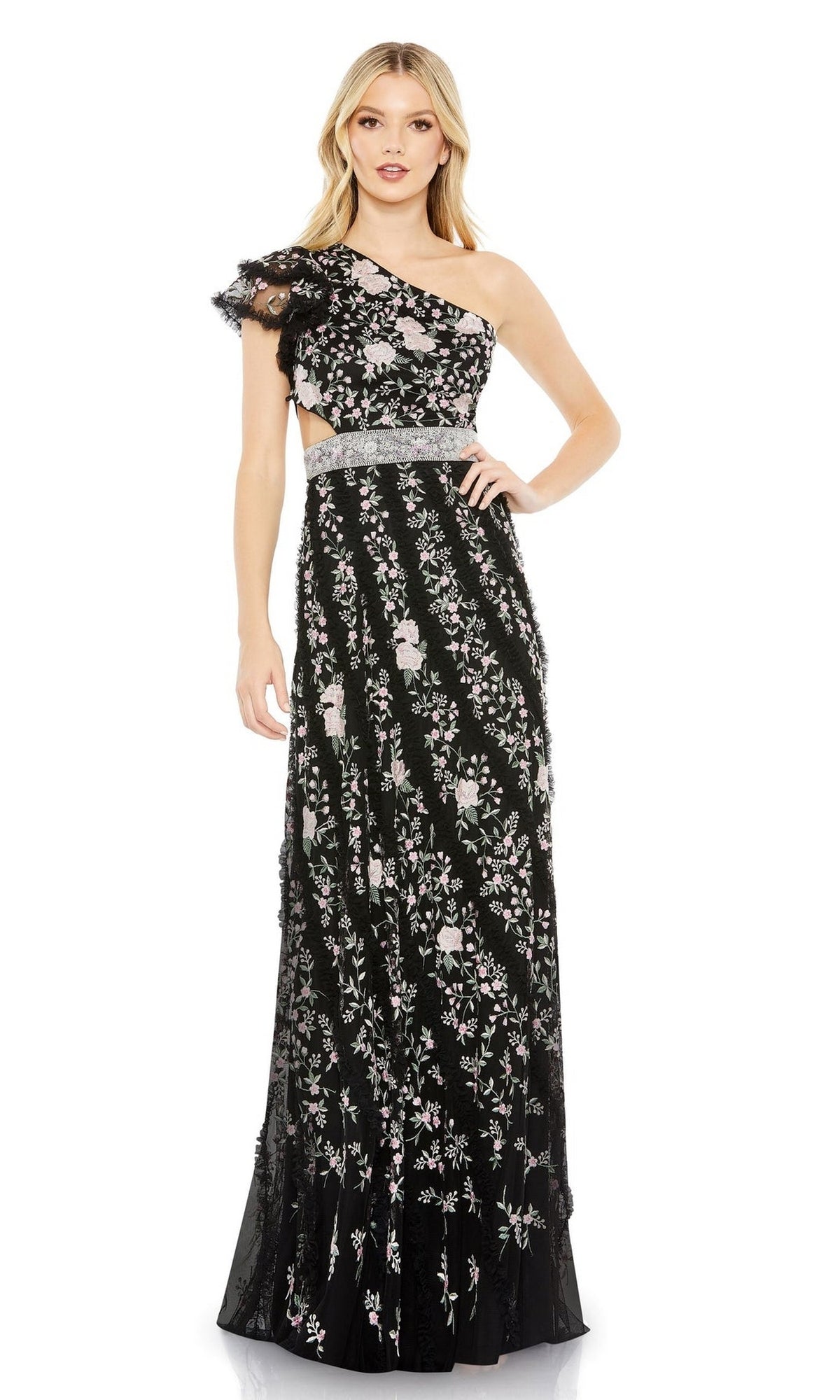 A woman wears the Long Formal Dress 70160 by Mac Duggal, a floor-length black gown featuring one shoulder, light floral embroidery, a sheer waist detail, and an elegant open back.